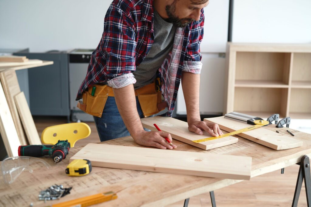 Carpenter measures the boards at the table Carpenter measuring wood for a home renovation project